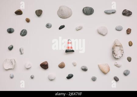 Muster mit Muscheln und Kieselsteinen auf weißem Hintergrund. Minimales Sommerkonzept. Kreative Urlaubsidee. Flach liegend. Meereshintergrund oder ozeanischer Hintergrund, Stockfoto