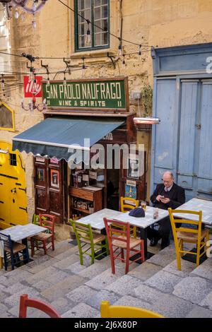 Ein Mann, der in einer Seitenstraße von Valletta, Malta, ein ruhiges Getränk genießt Stockfoto