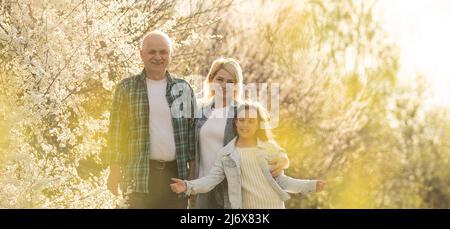 Ältere Großeltern mit Enkelkind im Frühjahr im Obstgarten. Stockfoto