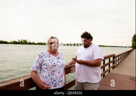 Mutter und Sohn entspannen sich am Ufer des Detroit River in Wyandotte, 11 Meilen stromabwärts von Detroit, Michigan, USA. Stockfoto