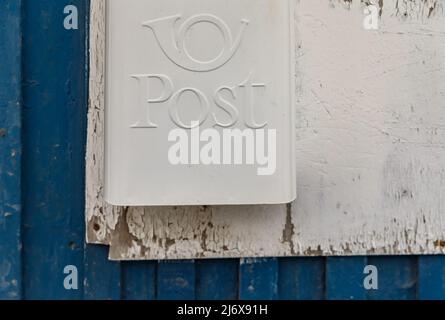 Weißer Briefkasten an der Holzwand des Hauses von blauer Farbe Stockfoto