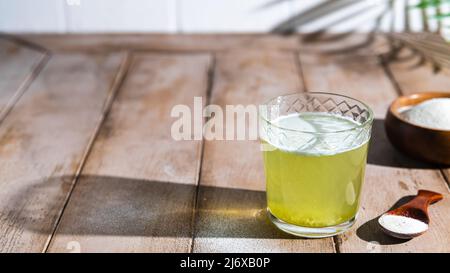 Kollagenpulver und Glas Wasser auf Holzgrund. Stockfoto