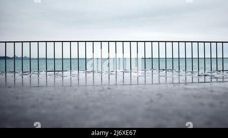 Regentag am Chicagoer Seeufer konzentriert sich auf Stahlgeländer. Blick über das Wasser mit Horizont in der Ferne Stockfoto