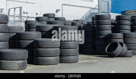 Haufen neuer Reifen. Viele Auto- und LKW-Reifen in einem Haufen. Straßenfoto, Niemand, selektiver Fokus Stockfoto