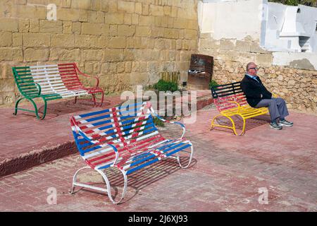 Bänke in den Farben verschiedener Nationalflaggen an der Strandpromenade von Qawra, Malta Stockfoto