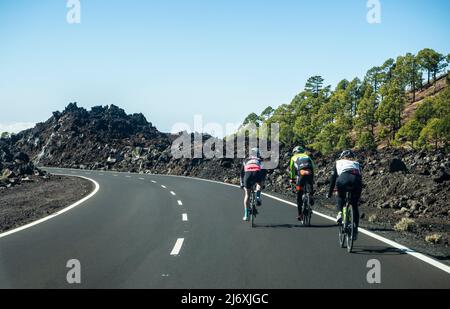 Eine Gruppe von Amateurradfahrern, die auf einer Straße mit vulkanischer Landschaft auf der Insel Teneriffa fahren. Stockfoto