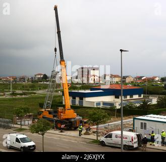 Erster Abschnitt des Mastes eines Turmdrehkrans, der von einem LKW-Kran auf einer Baustelle in Santander Cantabria Spanien in Position gehoben wird Stockfoto