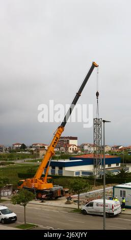 Erster Abschnitt des Mastes eines Turmdrehkrans, der von einem LKW-Kran auf einer Baustelle in Santander Cantabria Spanien in Position gehoben wird Stockfoto