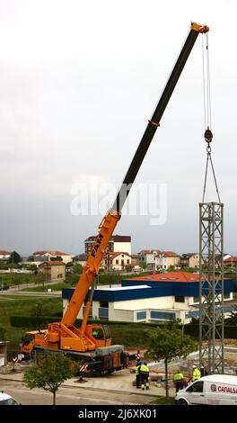 Erster Abschnitt des Mastes eines Turmdrehkrans, der von einem LKW-Kran auf einer Baustelle in Santander Cantabria Spanien in Position gehoben wird Stockfoto