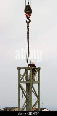 Ein Bauarbeiter, der die Ketten von der Maststrecke eines Turmdrehkrans aufhebt, nachdem er sie in die Position Santander Cantabria Spanien gebracht hat Stockfoto