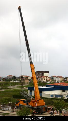 Zweiter Abschnitt des Mastes eines Turmdrehkrans, der von einem LKW-Kran auf einer Baustelle in Santander Cantabria Spanien in Position gehoben wird Stockfoto