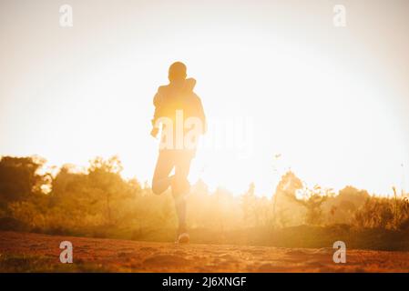 Ein kenianischer Läufer läuft bei Sonnenaufgang in der Stadt Iten in Kenia. Der Marathonläufer bereitet sich morgens auf das Rennen vor. Training Sport Laufen Foto Stockfoto