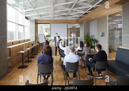 Der Business Coach kommuniziert mit einer Gruppe von erwachsenen Studenten während eines Seminars in der Weiterbildung. Stockfoto