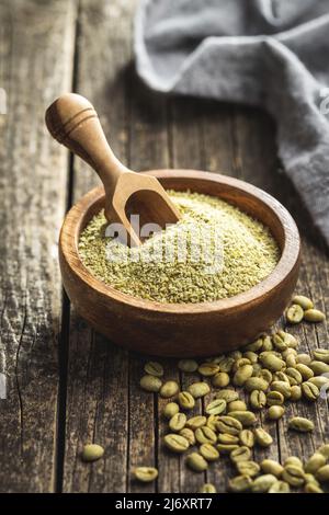Gemahlener grüner Kaffee in Holzschüssel und ungegeröstete Kaffeebohnen. Stockfoto