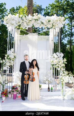 Mann und Frau Geiger auf Hochzeit Bogen Hintergrund. Stockfoto