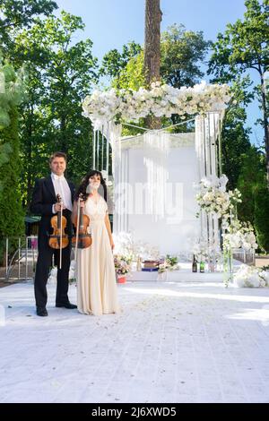 Mann und Frau Geiger auf Hochzeit Bogen Hintergrund. Stockfoto