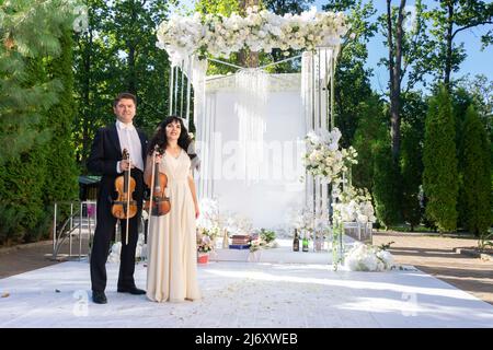 Mann und Frau Geiger auf Hochzeit Bogen Hintergrund. Stockfoto