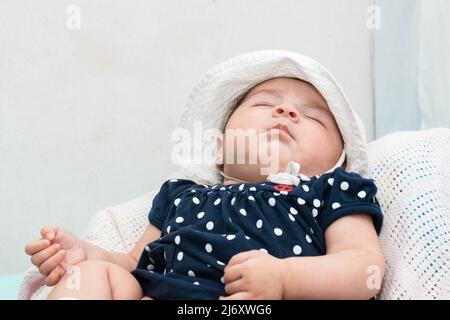 Schöne 4 Monate alte Latina schläft friedlich in ihrem Zimmer. Auf einem weißen Kissen liegend und friedlich träumend. Konzept der Ruhe. Stockfoto