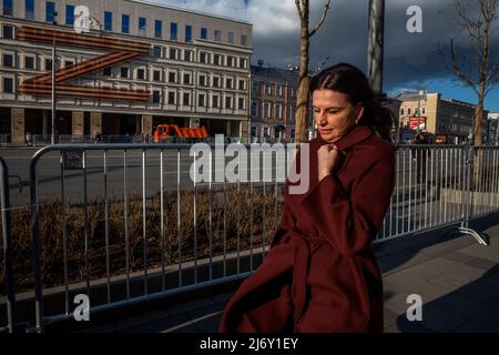 Moskau, Russland. 4.. Mai 2022. Die Menschen gehen auf dem Hintergrund des Gebäudes des Moskauer Theaters von Oleg Tabakov und dem Schild "Z" zur Unterstützung der besonderen militärischen Operation der russischen Streitkräfte in der Ukraine an der Fassade, auf der Gartenstraße im Zentrum von Moskau, Russland Stockfoto
