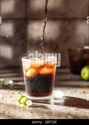 Kohlensäurehaltige Eiscola gießt in Glas, Partykonzept Stockfoto