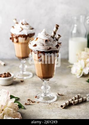 Schokoladenmilchshake mit Schlagsahne, Waffelrollen und Schokoladendeko Stockfoto