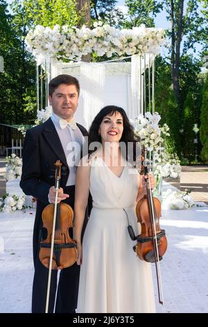 Mann und Frau Geiger auf Hochzeit Bogen Hintergrund. Stockfoto