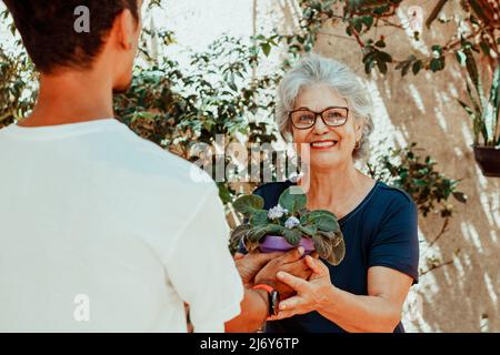 Glückliche interracial Familie. Sohn schenkt seiner Mutter im Hausgarten ein Geschenk. Stockfoto