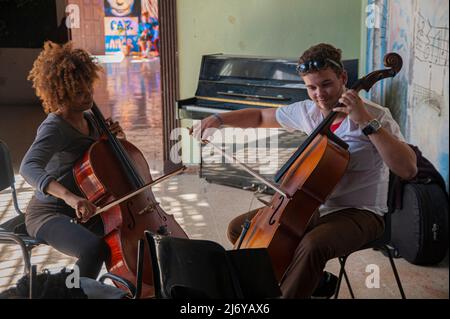 Junge Studenten Proben das Cello-Spiel in einer Schule in Matanzes, Kuba, mit einem Gemälde von John Lennon und Yoko Ono an der Wand hinter ihnen. Stockfoto