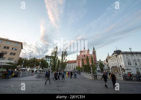 Bild von Menschen, die während eines sonnigen Sommers nach Ljubljana auf der Tromostovje-Brücke (Dreifachbrücke) zwischen dem Presernov-Platz und dem älteren Teil von Ljubljana wandern Stockfoto