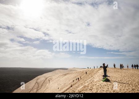 Bild von Menschen, die an einem sonnigen Nachmittag die Pyla Sand Düne erklimmen. Die Düne von Pilat (Dune du Pilat auf Französisch, oder Pyla) ist der höchste Sanddun Stockfoto