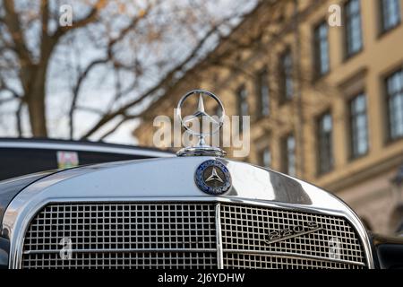 Mercedes-Benz W111 220 S Frontemblem eines schwarzen Autos. Klassisches deutsches Auto mit glänzendem Chrom-Frontgrill und einem Kühlerfigur. Stockfoto