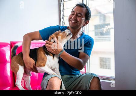 Ein Mann streicheln seinen Hund Beagle, tierfreundliches Liebeskonzept Stockfoto