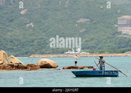 Ein Einheimischer rudert sein kleines Boot in der Nähe des Nordufers der Peng Chau Insel, Hongkong. Stockfoto