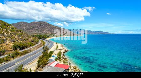 Die Küstenstraße in der Bucht Ca Na, Binh Thuan von oben mit dem Boulevard und der Eisenbahn gesehen, gilt die Küste nahe beieinander als eine schöne Bucht Stockfoto