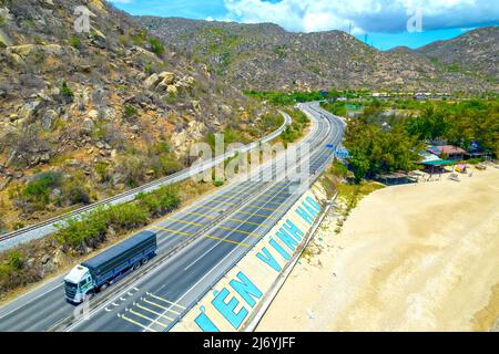 Die Küstenstraße in der Bucht Ca Na, Binh Thuan von oben mit dem Boulevard und der Eisenbahn gesehen, gilt die Küste nahe beieinander als eine schöne Bucht Stockfoto