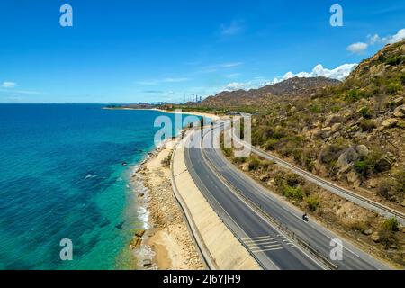 Die Küstenstraße in der Bucht Ca Na, Binh Thuan von oben mit dem Boulevard und der Eisenbahn gesehen, gilt die Küste nahe beieinander als eine schöne Bucht Stockfoto