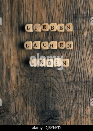 Holzwürfel mit den deutschen Worten lieben, lachen und leben auf einem rustikalen Holztisch Stockfoto