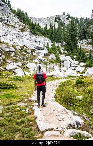 Ein junger Mann, der auf dem Granite Mountain Trail wandert und auf den Aussichtspunkt oben, die Central Washington Cascades, blickt. Stockfoto