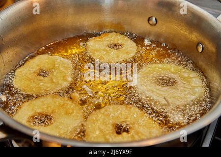 Kochen von Apfelpfannkuchen. Apfeldonut in kochendem Öl. Stockfoto