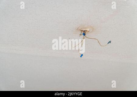 Gefährliche schlechte Verkabelung, die an der Decke hängt Stockfoto