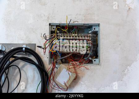 Offene Anschlussdose mit hervorstehenden Drähten, vorbereitet für die Montage und den Anschluss von Telefon- und Computerkabeln. Selektiver Fokus Stockfoto