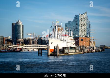 Vorderansicht des berühmtesten historischen Frachtschiffes Hamburgs mit dem Überseebrücke und dem niederhafen im Hintergrund vor einem stilvollen Konzertsaal. Stockfoto