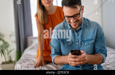 Junges Paar mit Smartphone mit Streit und Ehekonflikt wegen Betrug Stockfoto