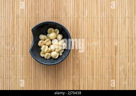 Süße Lotuskerne auf einer kleinen Schüssel. Lotus-Bohnen aus der Dose als traditionelles asiatisches Essen, Snack von oben Stockfoto