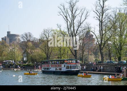 Menschen, die einen sonnigen Frühlingstag auf dem Flussweg der Themse genießen und Motorboote mieten. Windsor Castle im Hintergrund. England, Großbritannien. Stockfoto