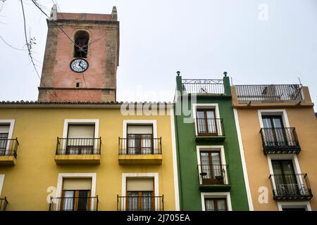 Farbenfrohe Fassaden in Villajoyosa. Glockenturm der Marienkirche Asuncion im Hintergrund. Stockfoto