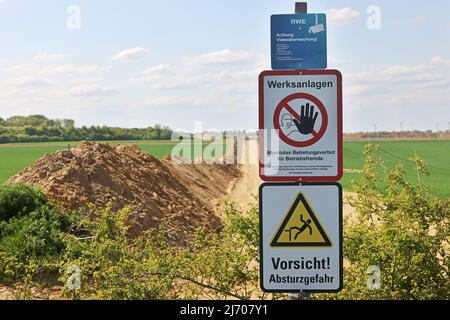 03. Mai 2022, Nordrhein-Westfalen, Erkelenz: Die Grenzmauer ist hinter Warnschildern am Tagebau Garzweiler zu sehen. Foto: Oliver Berg/dpa Stockfoto