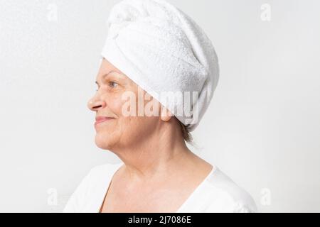 Kaukasische ältere Frau mit Falten und weißem Handtuch auf dem Kopf Stockfoto