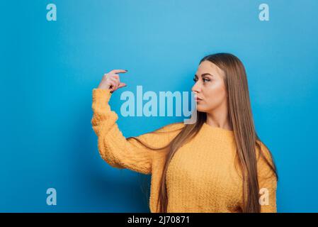 Frau, die etwas in der Hand hält, während sie auf einem isolierten Hintergrund steht. Stockfoto