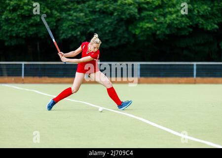 Junge Frau Hockeyspielerin schlug den Ball in Angriff auf Spiel Stockfoto